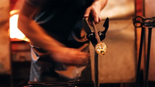Glass Blower Shaping Glass Sculpture with Tool