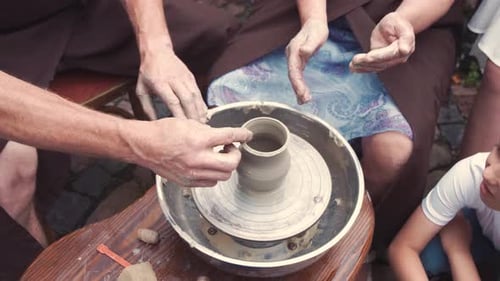 Grandmother with a Grandchildren Make Pitchers in Pottery