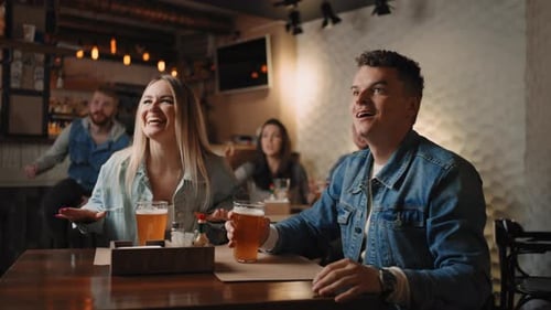 A Group of Friends of Men and Women in a Pub Together Cheer for Their National Team at the World Cup