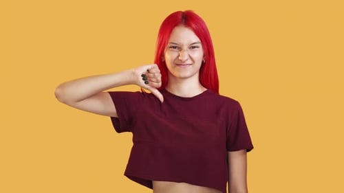 Young Woman Giving Thumbs Down on Yellow Background