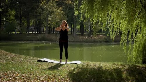 The Girl Performs Warmup Exercises Before Yoga in Nature n Park
