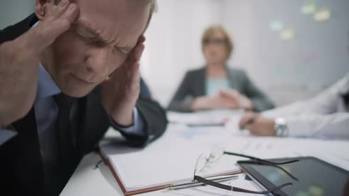 Man Experiencing Pain at Meeting With Colleagues