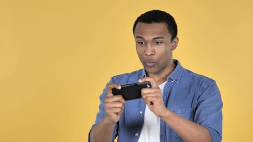 Young Adult Playing Mobile Game on Phone Wins
