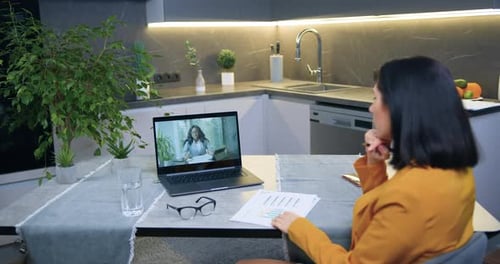 Femme assise à la table de la cuisine et écoutant attentivement l'explication d'une collègue