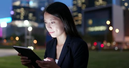 Woman Works on Tablet in City Park at Night