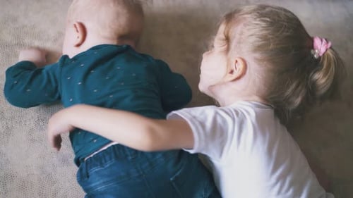 Two Young Children Cuddle on a Couch