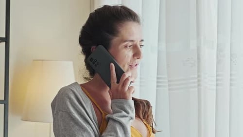 Woman Talking on Mobile Phone Indoors by Window