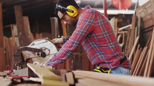 Carpenter working on woodworking machines in carpentry shop
