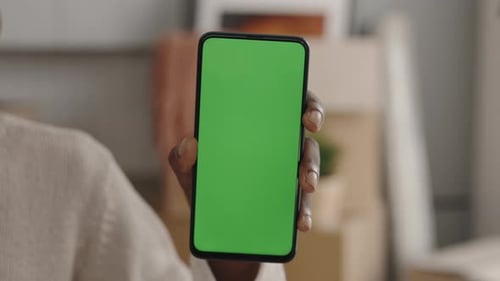 Closeup of African American Female Hand Holding Green Chroma Key Screen Smartphone Indoors in Light