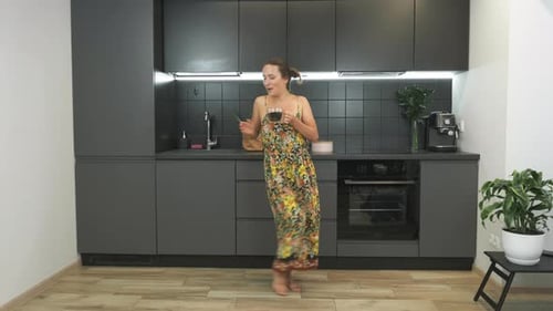 Woman Dances Barefoot in Kitchen with Drink