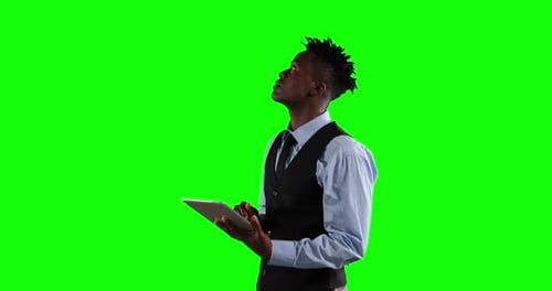an African American man in suit using a phone in green background