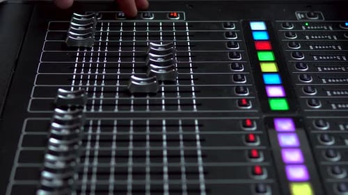 Man Works on a Professional Electronic Audio Mixer. A Control Panel for Tuning Sound Channels