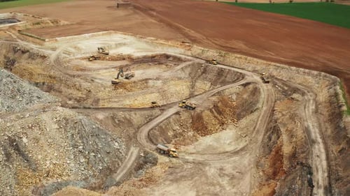 Luftaufnahme von Lastwagen und Baggern, die in einem Steinbruch Bergbau betreiben