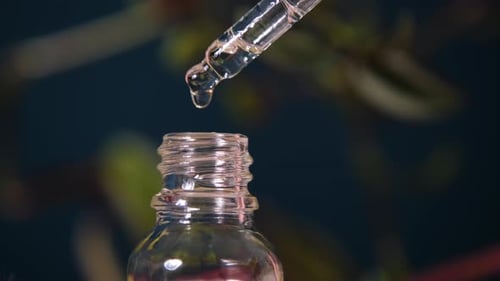 Clear Liquid Dripping into Glass Bottle from Dropper