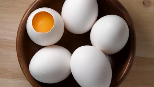 White chicken eggs rotating in wooden bowl top view