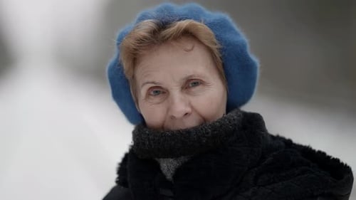Portrait of an Elderly Woman in Winter Clothes Standing Outdoors in a Park in Winter Looking at the