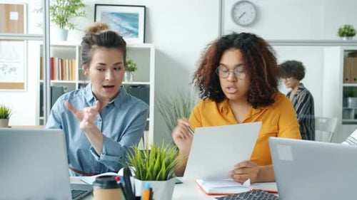 Women Discussing Business Documents in Modern Office