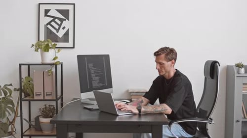 Programmer Typing Program Code on Laptop in Office