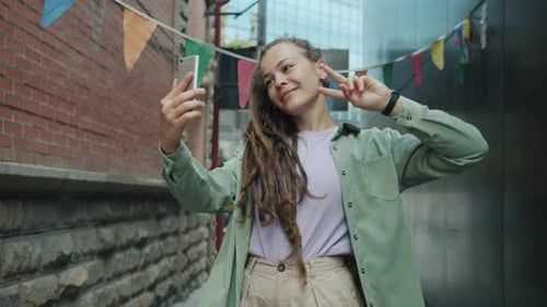 Pretty Young Lady with Dreads Taking Selfie with Smartphone Camera Having Fun Outdoors in City