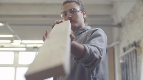 Caucasian Man Checking Trimmed Wood Board at Carpentry Workshop