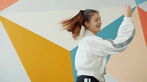 Portrait of Pretty Young Brunette Dancing Indoors in Studio and Looking at Camera