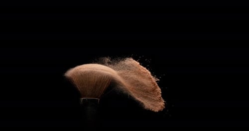 Bronze Powder Exploding From a Makeup Brush
