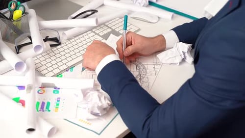 Man Working at Desk with Blueprints and Computer