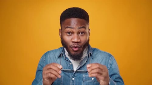 Smiling Man Removing His Glasses in Studio