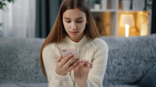 Young Woman Using Smartphone on Couch