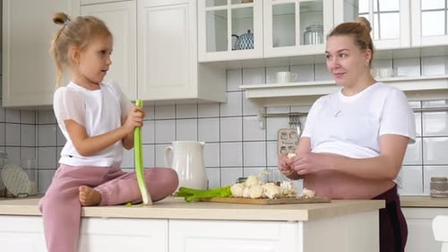 Child and Woman Preparing Food Together in Kitchen