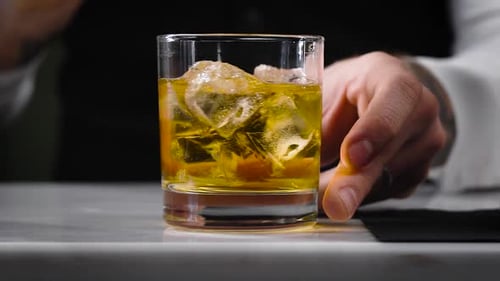 Bartender Mixing Cocktail Drink with Ice in Glass