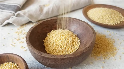 Millet being Poured into Wooden Bowl Close Up