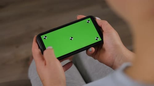 Closeup of a Woman Holding a Phone with a Green Screen at Home
