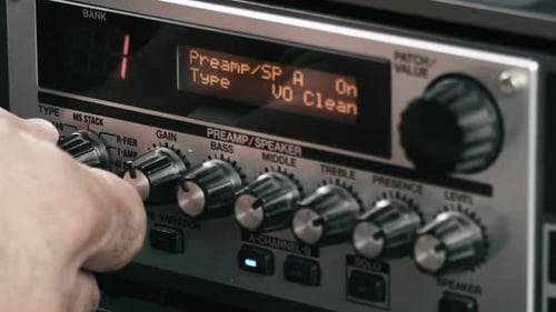 Musician's hand changes speaker settings of a guitar preamp multi effect, close up.