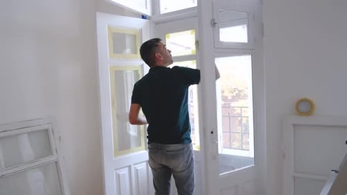 Man Paints White Door Frame Indoors