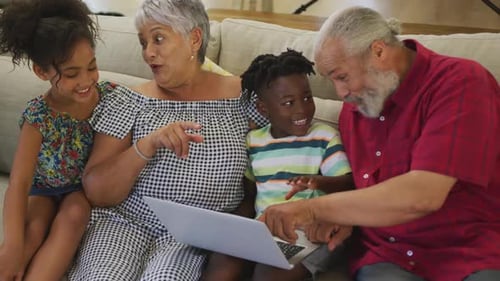 Grandparents and Grandchildren Using Laptop Together on Couch