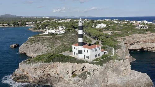 Portocolom lighthouse on rocky cliff at the sea, Mallorca, Spain