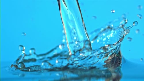 Super Slow Motion Water Falls on the Table on a Blue Background