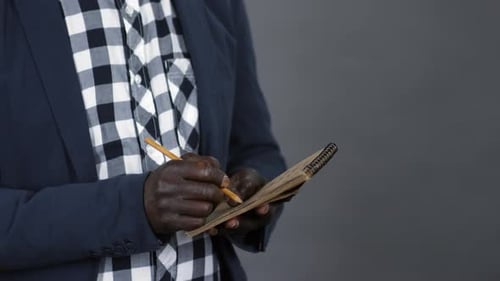 Hands of African Man Writing in Notepad
