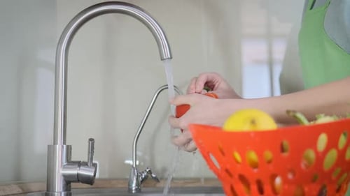Woman Washing Red Pepper in Kitchen Sink