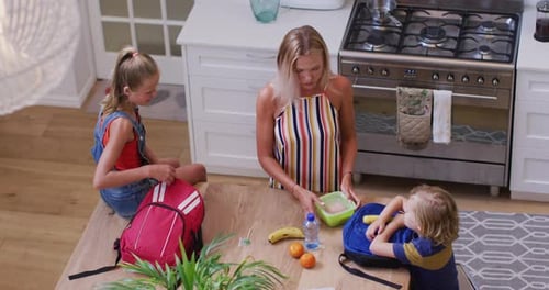 Mother and Children Packing Lunches in Kitchen