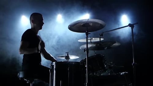 Musiker spielt eine Melodie auf dem Schlagzeug, Schwarzer Rauchhintergrund, Seitenansicht, Silhouetten, Zeitlupe