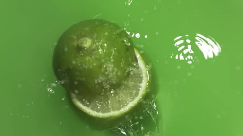 Bright Green Lime Plunging into Clear Water