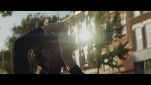 Young Man Photographs with Vintage Camera in City