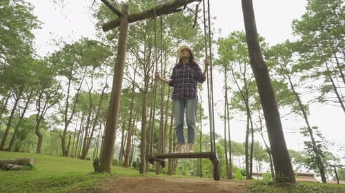 Happy Asian woman swinging on a swing in forest trees