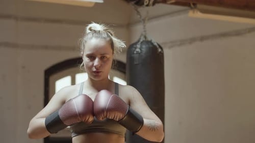 Front View of Female Boxer in Boxing Gloves Standing in Gym