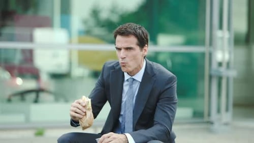 Businessman Eating Sandwich and Drinking Soda Outside