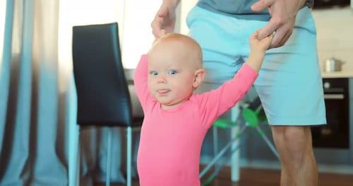 Infant Taking First Steps With Adult Support