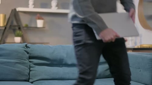 Man Opens Laptop on Couch in Cozy Home