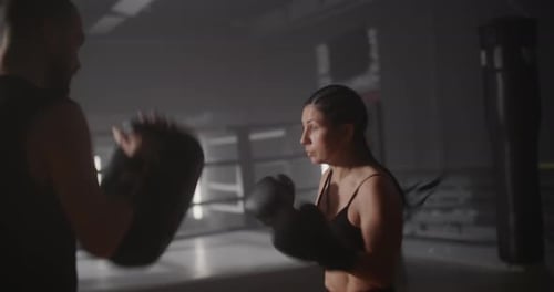 Woman Kickboxing with Trainer in Boxing Ring